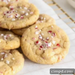 Dreamy Peppermint White Chocolate Pudding Cookies 12 A pile of cookies with peppermint bits and white chocolate on a parchment lined cooling rack.