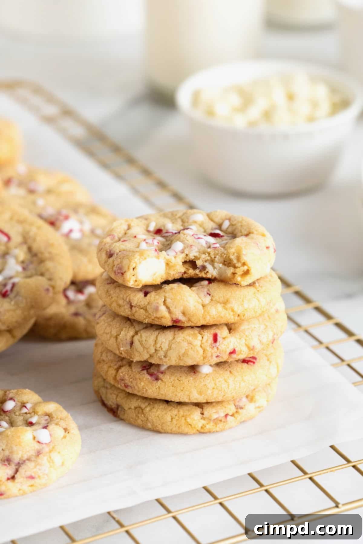 Dreamy Peppermint White Chocolate Pudding Cookies 3 Five delectable peppermint white chocolate cookies, artfully stacked on a parchment-lined metal cooling rack, showcasing their inviting texture and festive toppings.