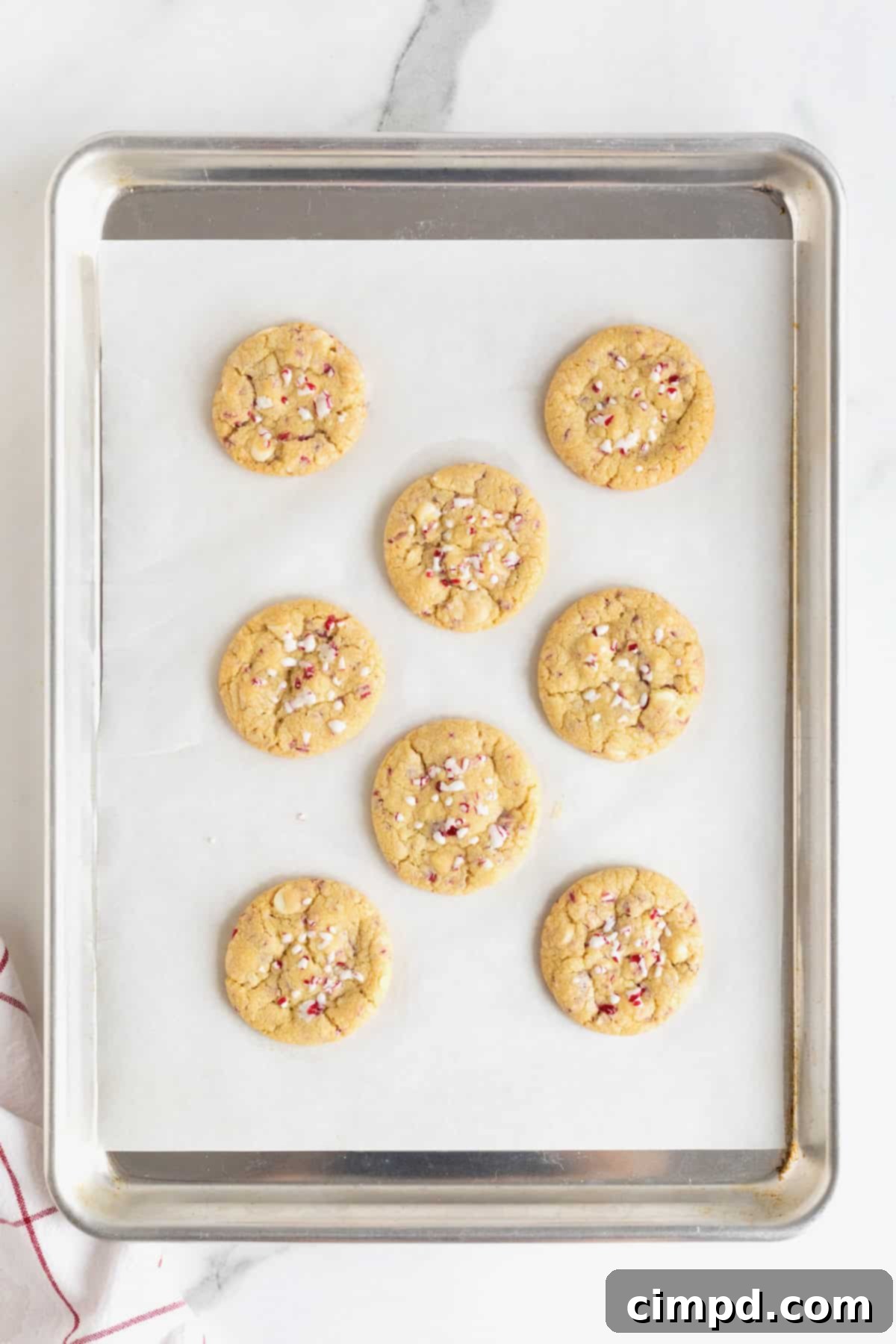 Dreamy Peppermint White Chocolate Pudding Cookies 9 Eight perfectly baked cookies arranged on a parchment-lined aluminum baking sheet, showcasing their golden edges and inviting texture, ready to cool.