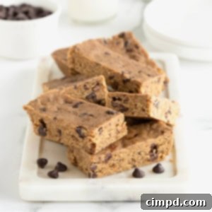 Seven breakfast bars piled on a white, rectangle-shaped board on top of a white marble counter.