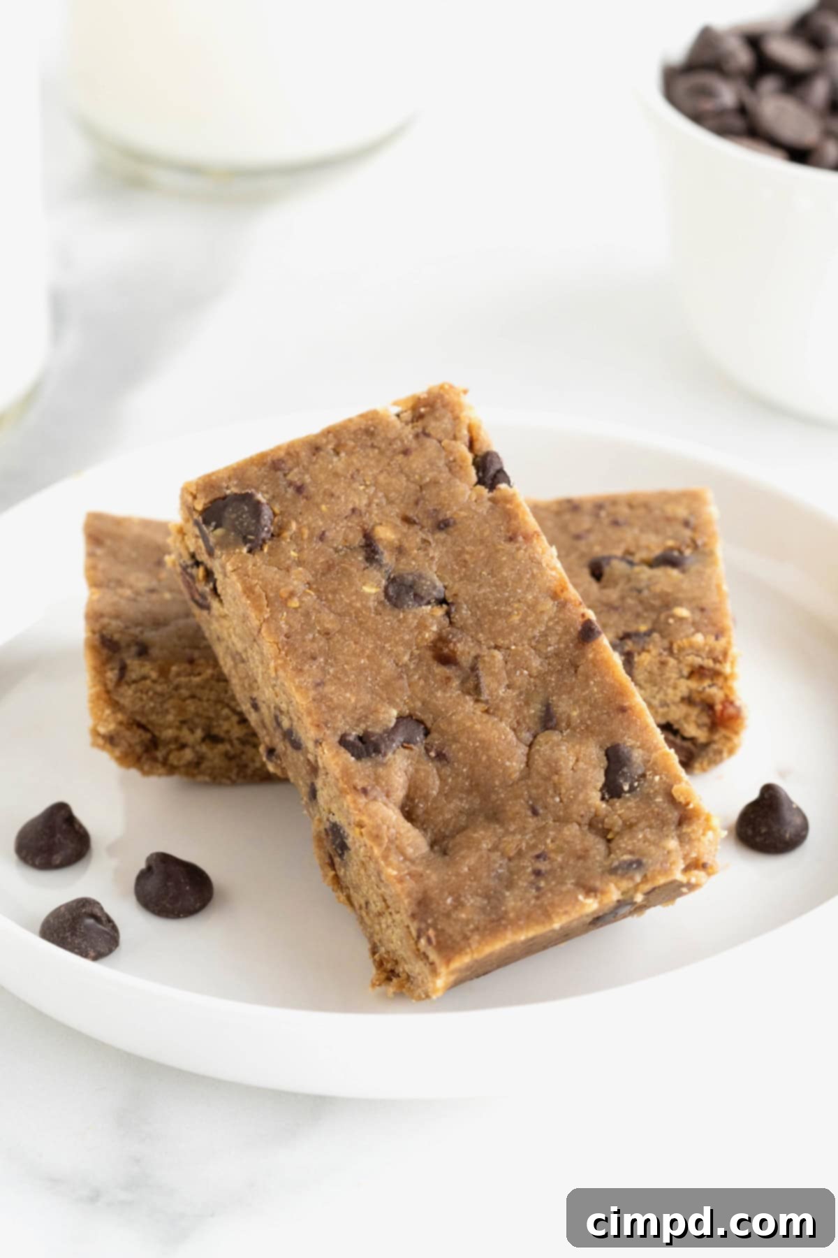 Two peanut butter chocolate chip breakfast bars on a small white plate, with a few chocolate chips scattered around.
