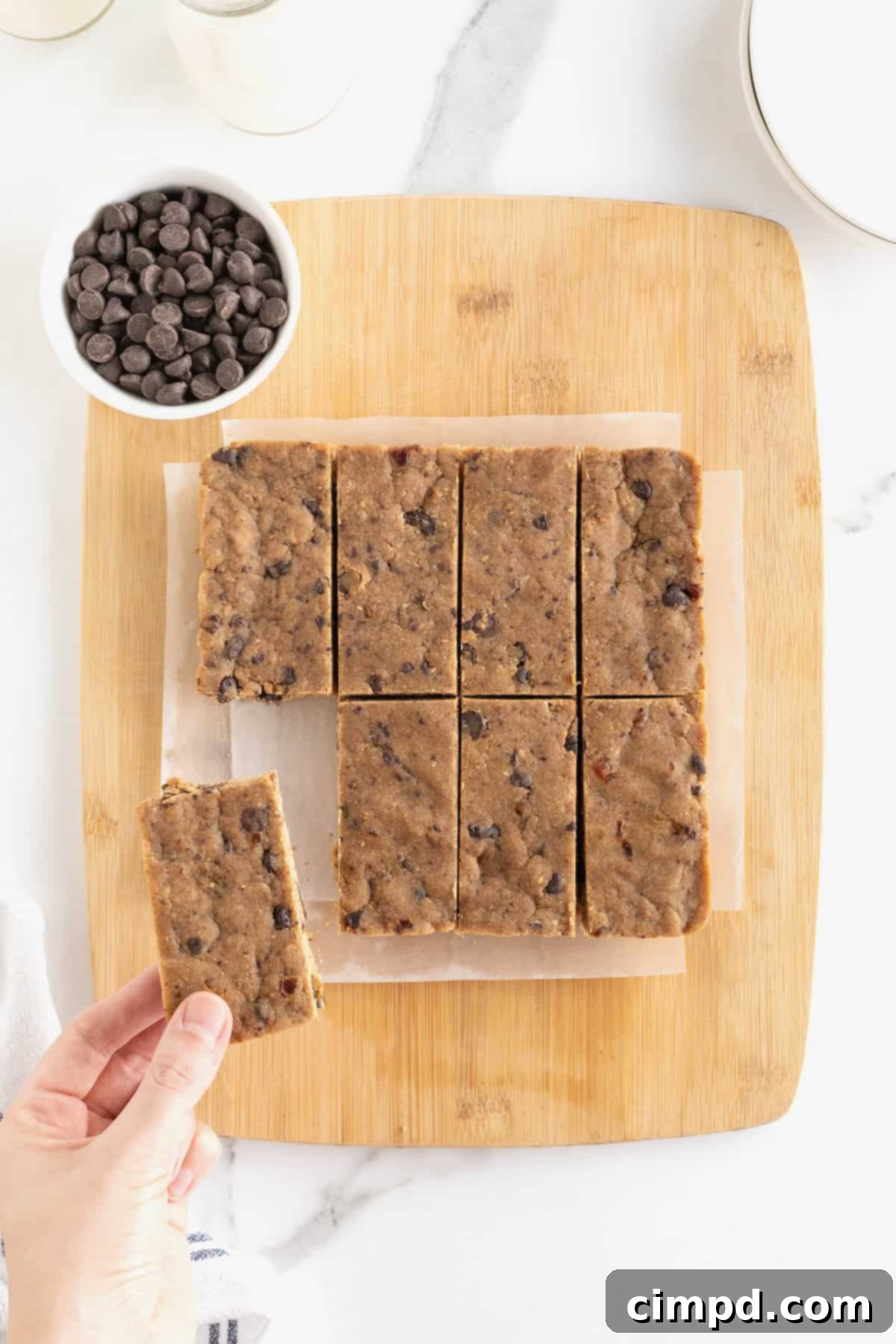 10 peanut butter chocolate chip breakfast bars displayed on a parchment-lined light wood cutting board, freshly cut and ready to serve.