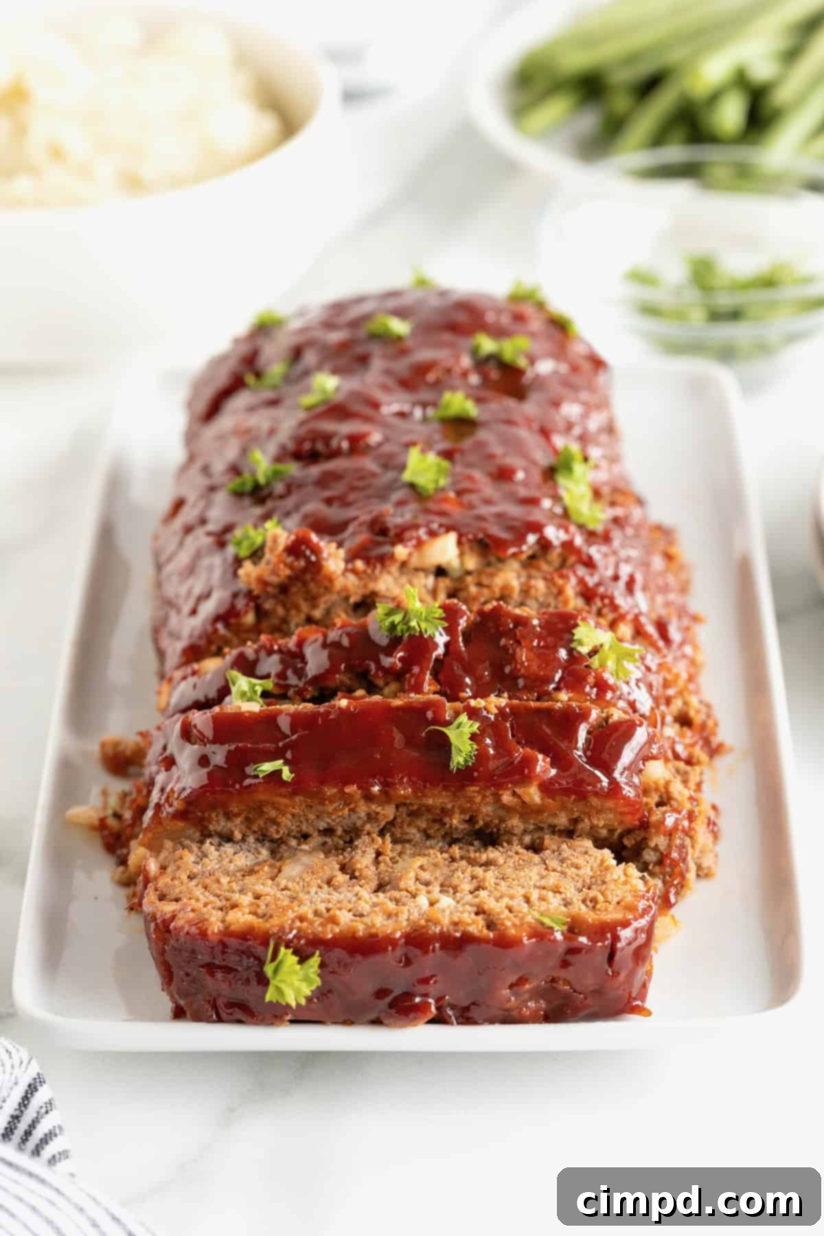 A beautifully garnished classic meatloaf on a rectangular, white-rimmed serving plate, ready to be sliced and served for a family meal.