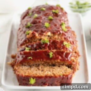 A meatloaf garnished with parsley on a rectangular, white rimmed serving plate.