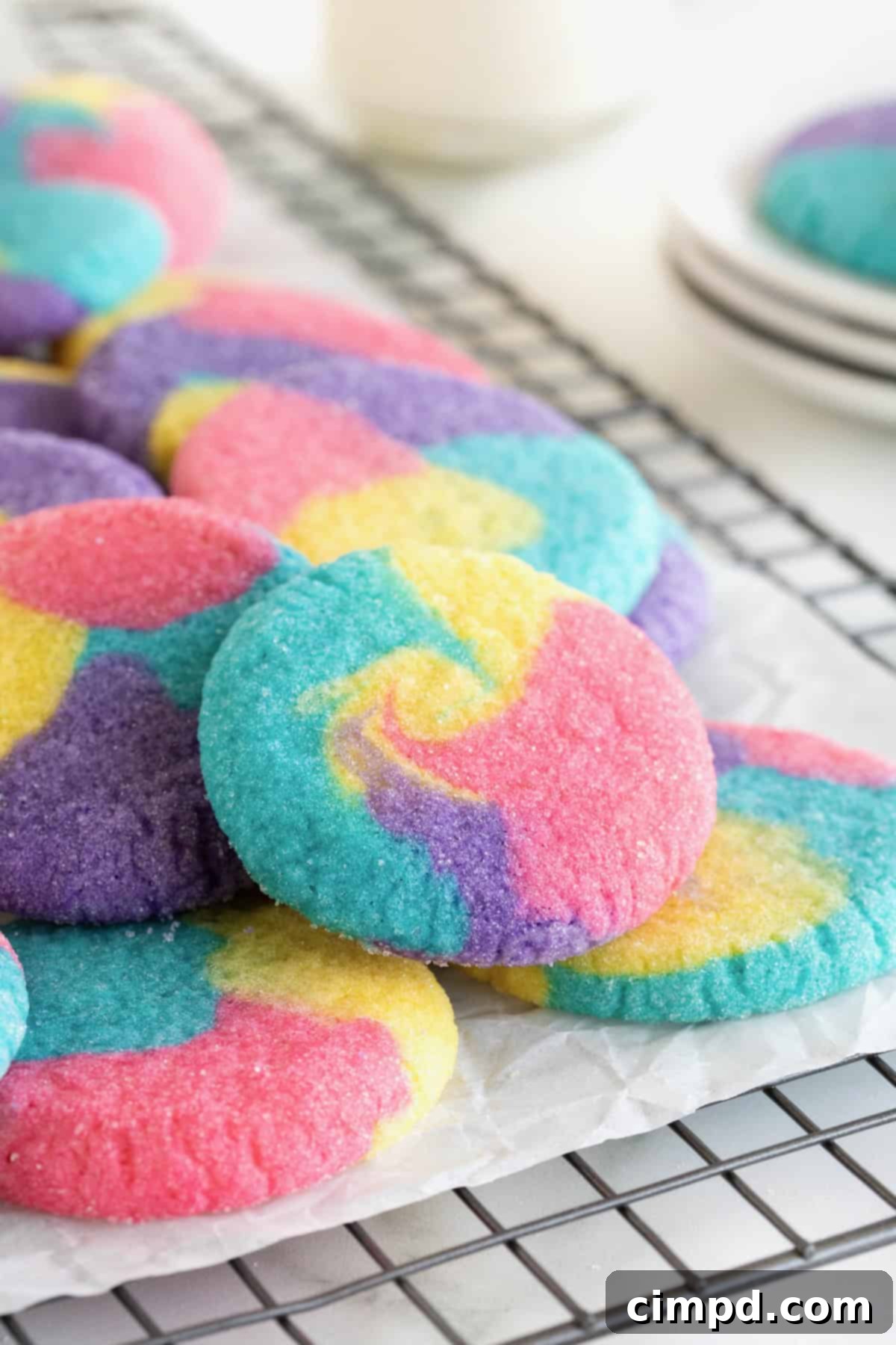 Vibrant Swirl Sugar Cookies 11 A neatly stacked pile of tie-dyed sugar cookies resting on a parchment-lined cooling rack, allowing them to cool completely.