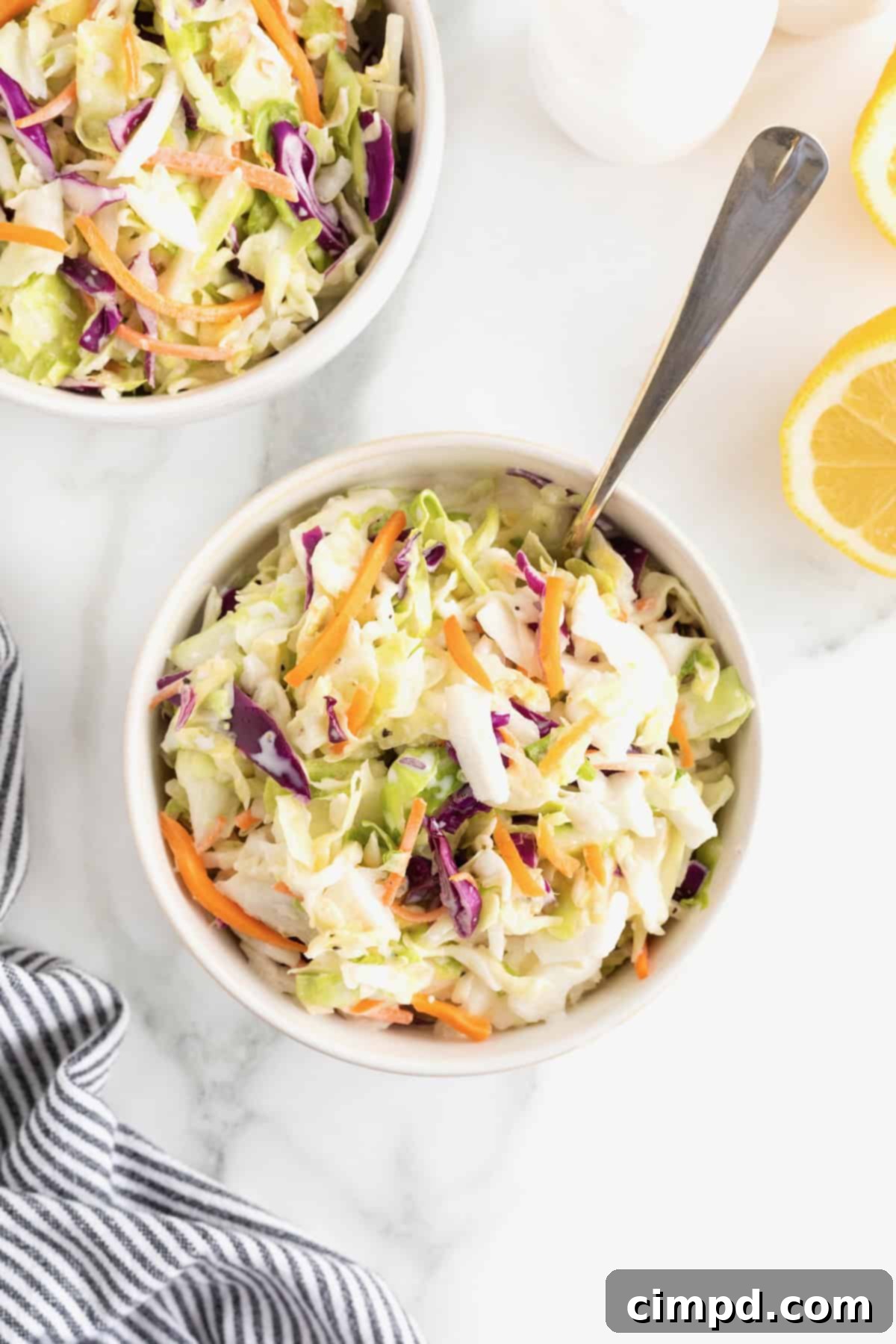 Two white salad bowls generously filled with freshly made coleslaw, ready to be served.