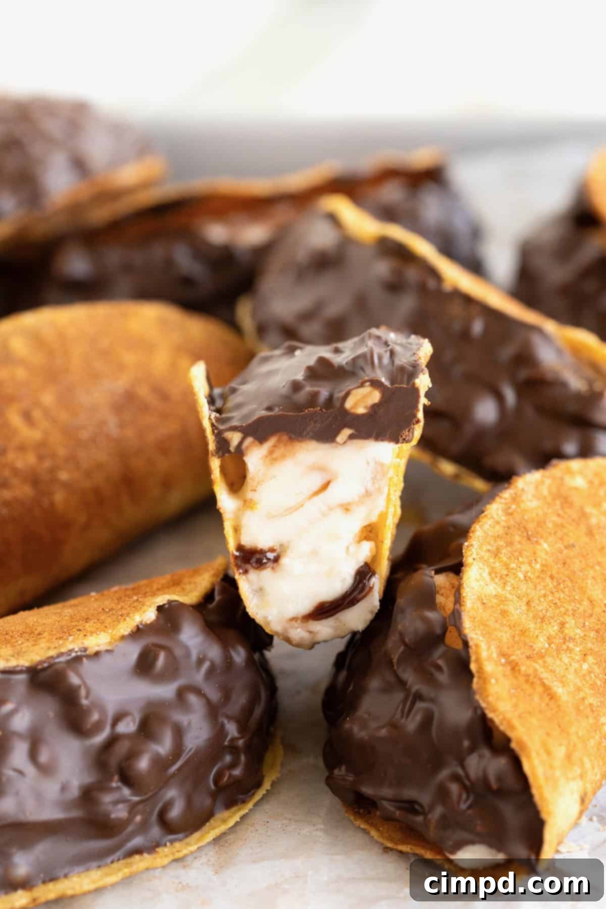 Frozen Chocolate Taco Treats 4 A delectable pile of homemade choco tacos. The top taco is cut in half, showcasing the beautiful swirls of fudge ripple ice cream.