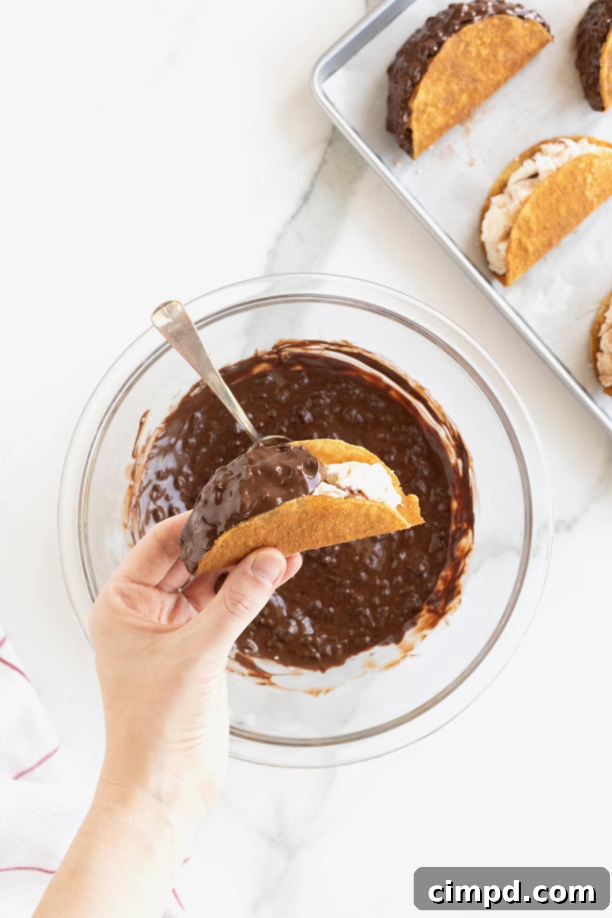 Frozen Chocolate Taco Treats 9 A hand expertly holding a choco taco, half of which is beautifully coated in the chocolate peanut topping, with the ice cream peeking out.