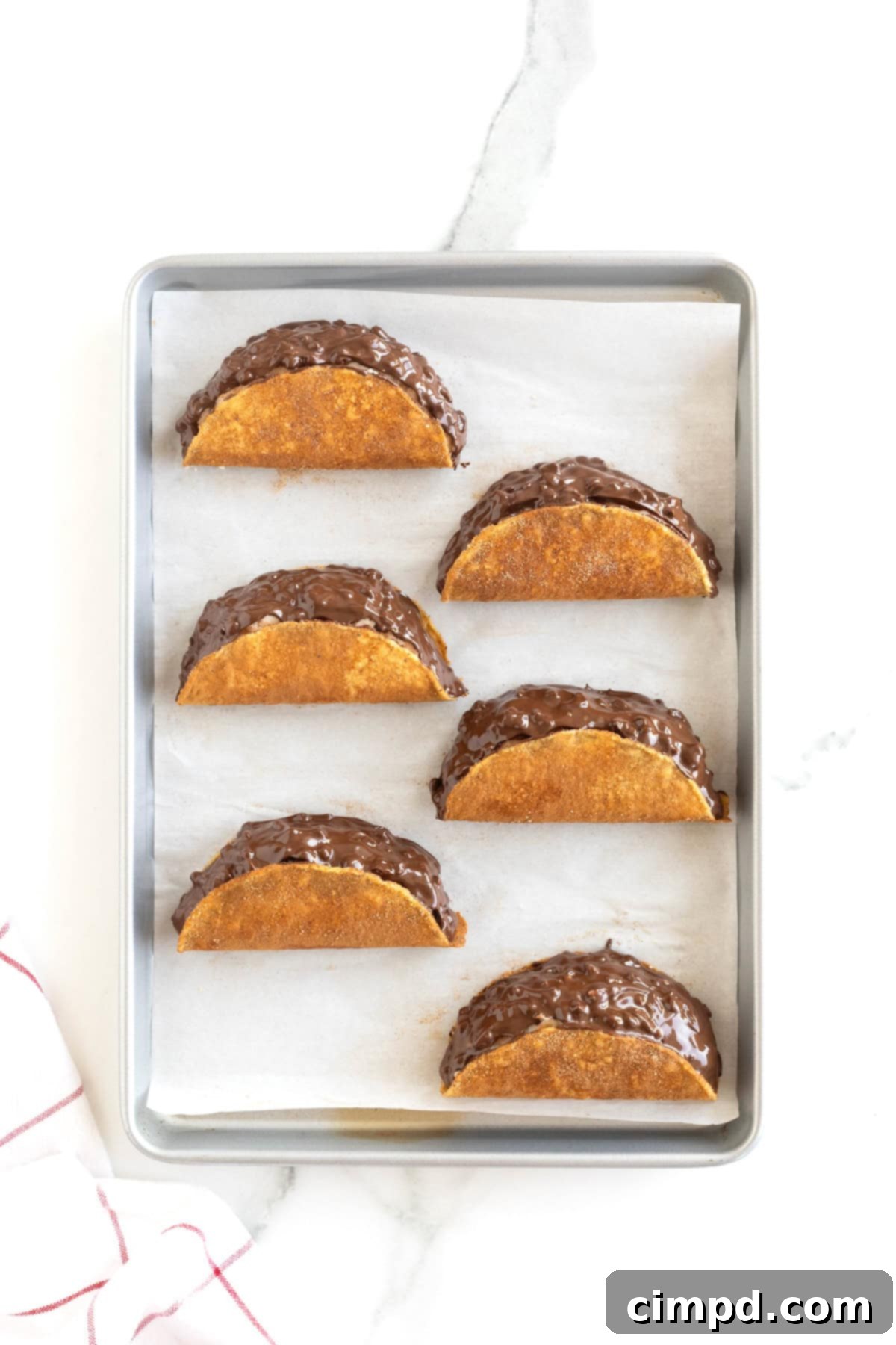 Frozen Chocolate Taco Treats 10 Six perfectly finished homemade choco tacos resting on a parchment-lined aluminum baking sheet, frozen and ready to eat.