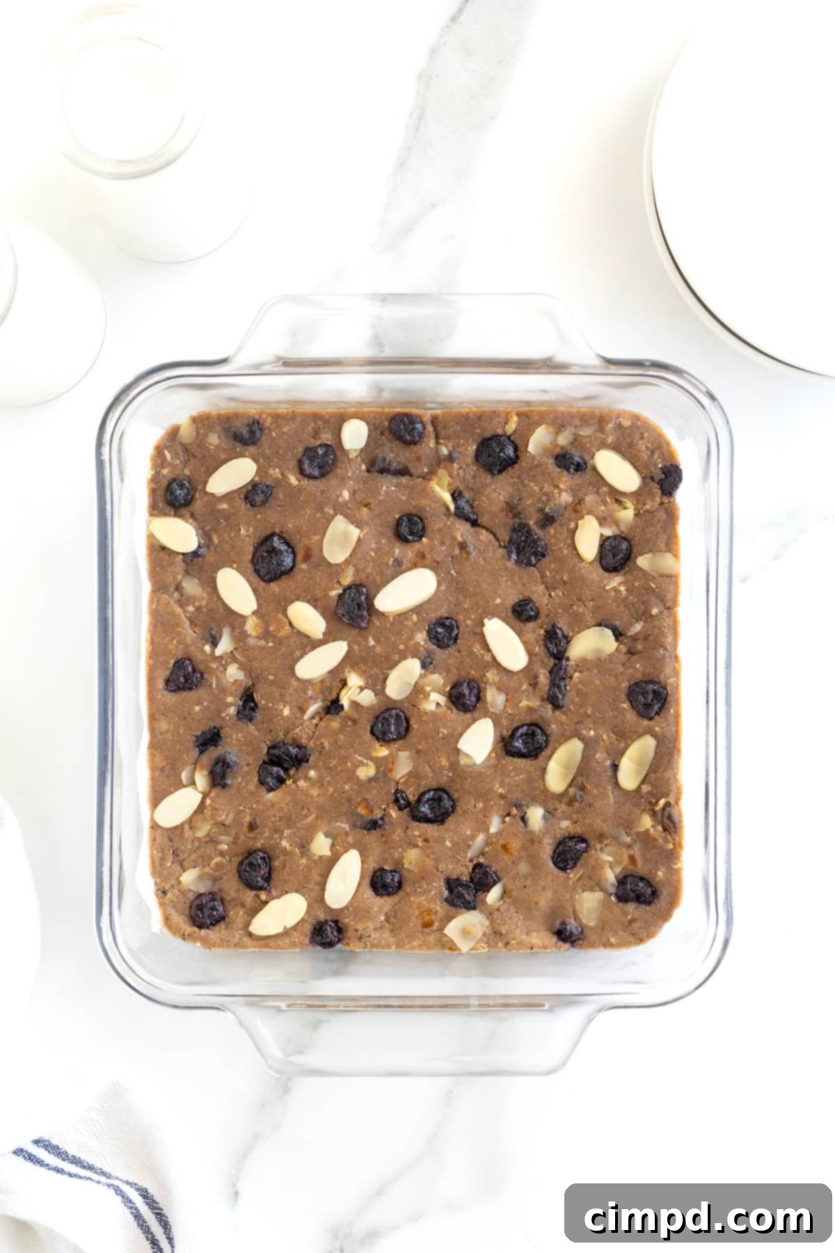 Sunrise Blueberry Banana Almond Bars 7 A square glass baking dish filled with the breakfast bar mixture, topped with an artful sprinkle of dried blueberries and slivered almonds, ready for chilling.