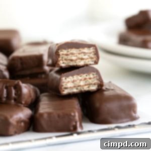 Quick Homemade KitKat Bites 13 A perfect stack of homemade Kit Kat candy bar bites, glistening with chocolate, arranged neatly on a parchment-lined cooling rack, ready to be enjoyed.
