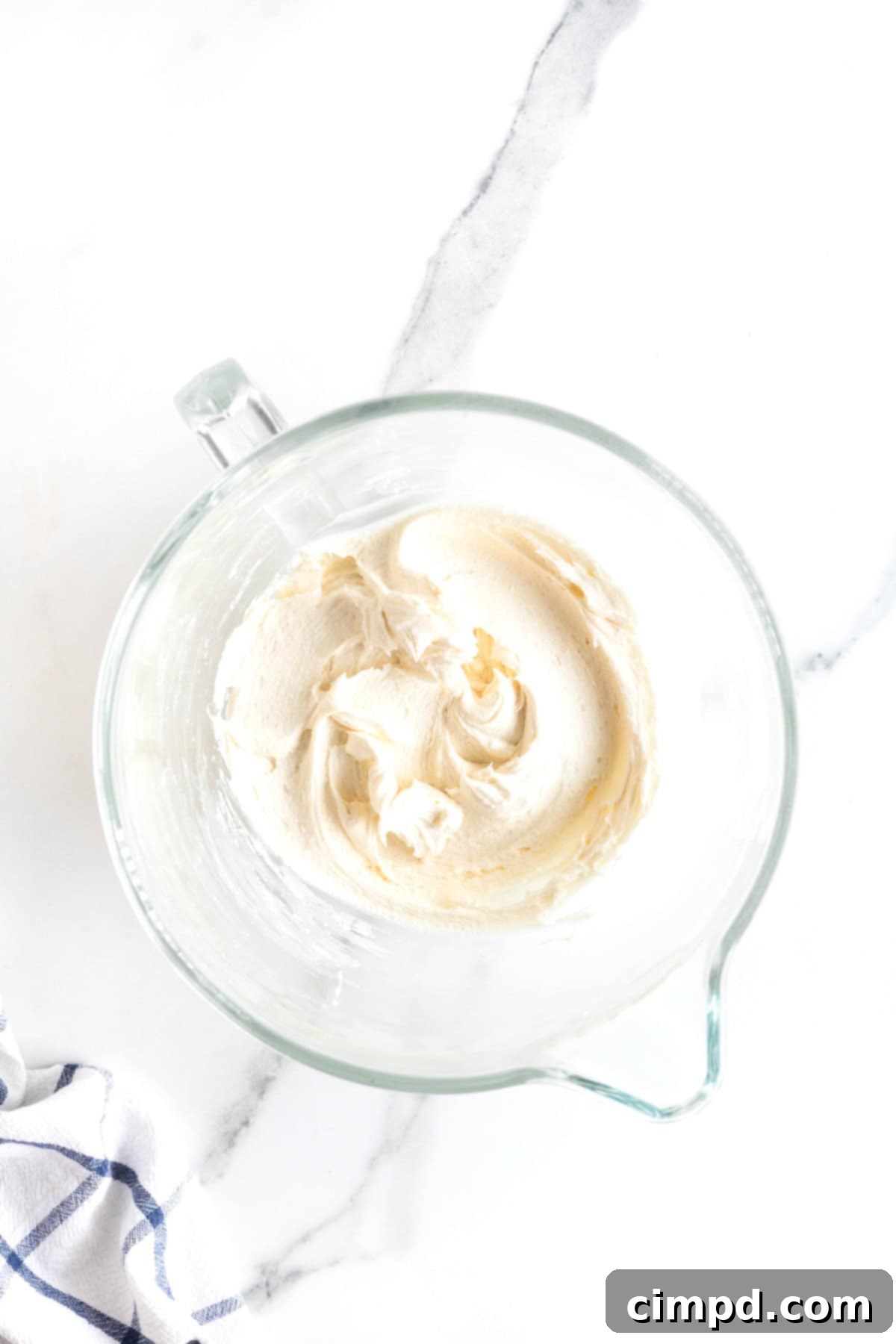 Foolproof Buttercream Frosting 7 A glass bowl of buttercream frosting on a white marble counter.