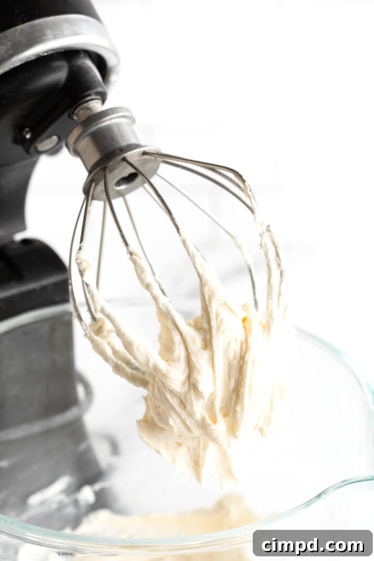 Foolproof Buttercream Frosting 8 A whisk attachment from an electric mixer with white buttercream frosting on it.