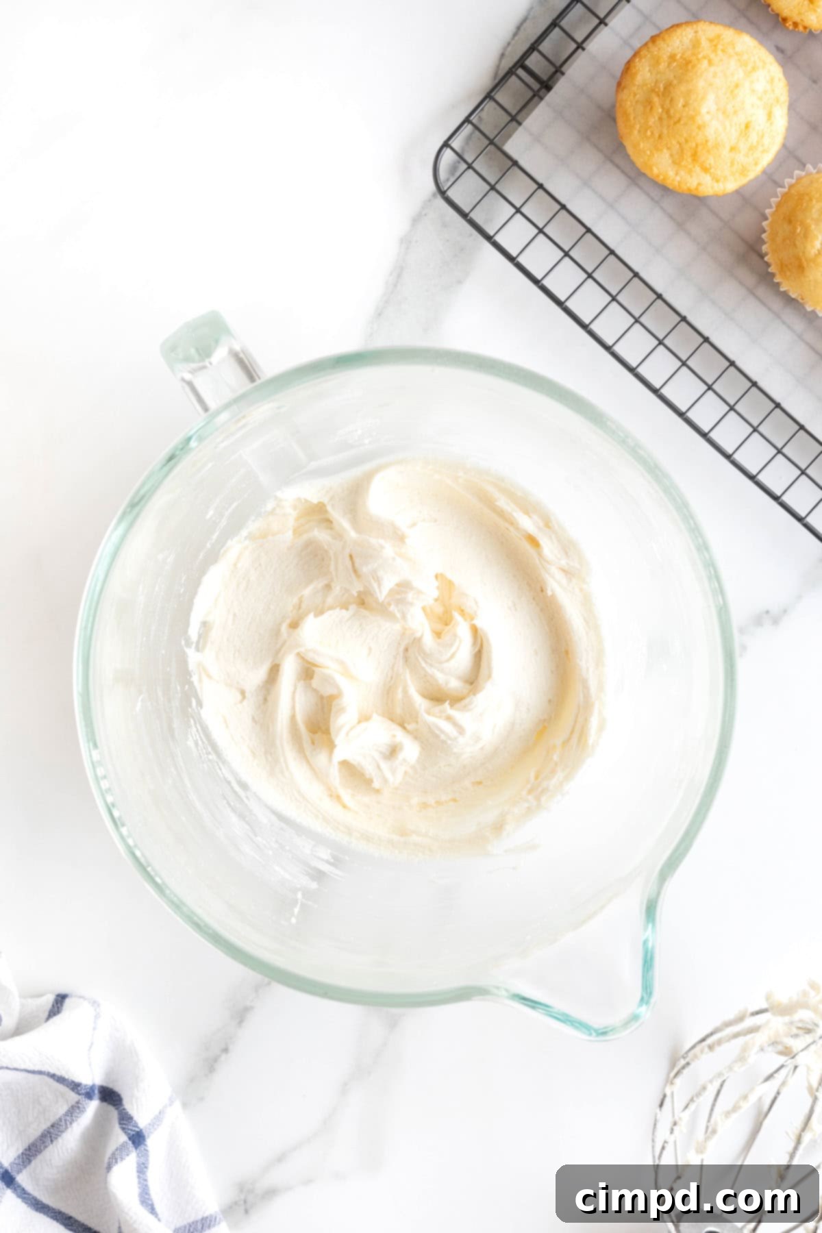 Foolproof Buttercream Frosting 10 A glass bowl of buttercream frosting on a white marble counter.