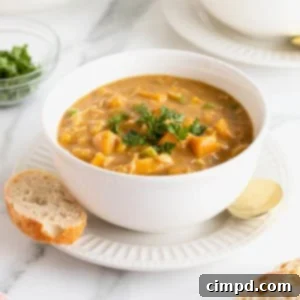 A white bowl of pumpkin pot pie soup on a white fluted plate.