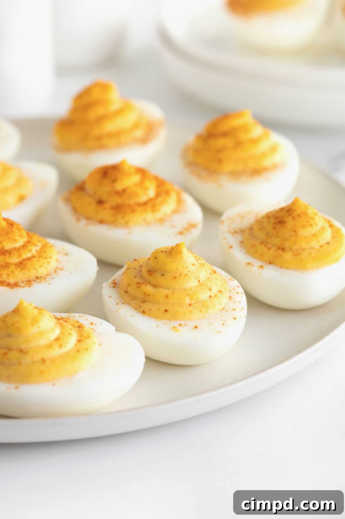 Devilish Delights 8 A beautifully presented large white serving platter of classic deviled eggs, ready to be enjoyed, sitting on a white marble counter.