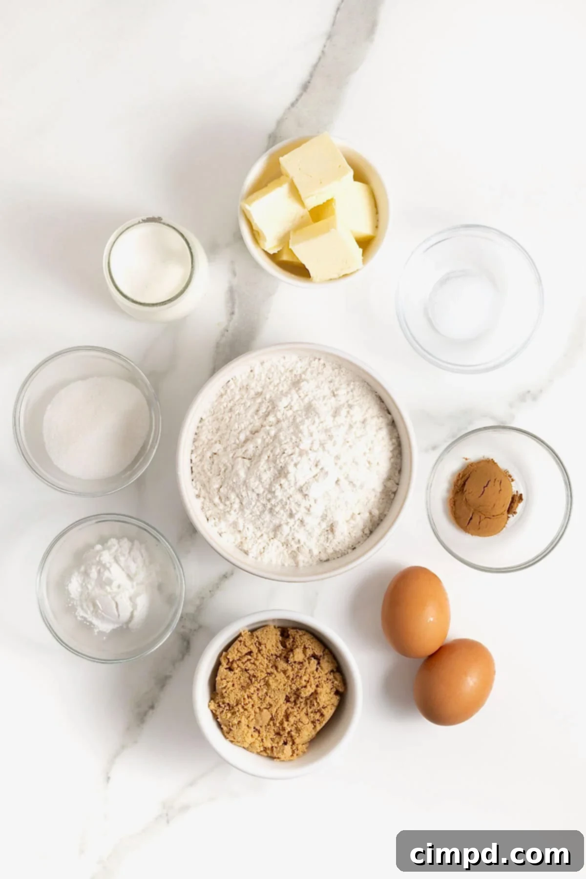Ingredients for snickerdoodle scones are neatly arranged in small glass dishes on a white marble countertop, ready for baking.
