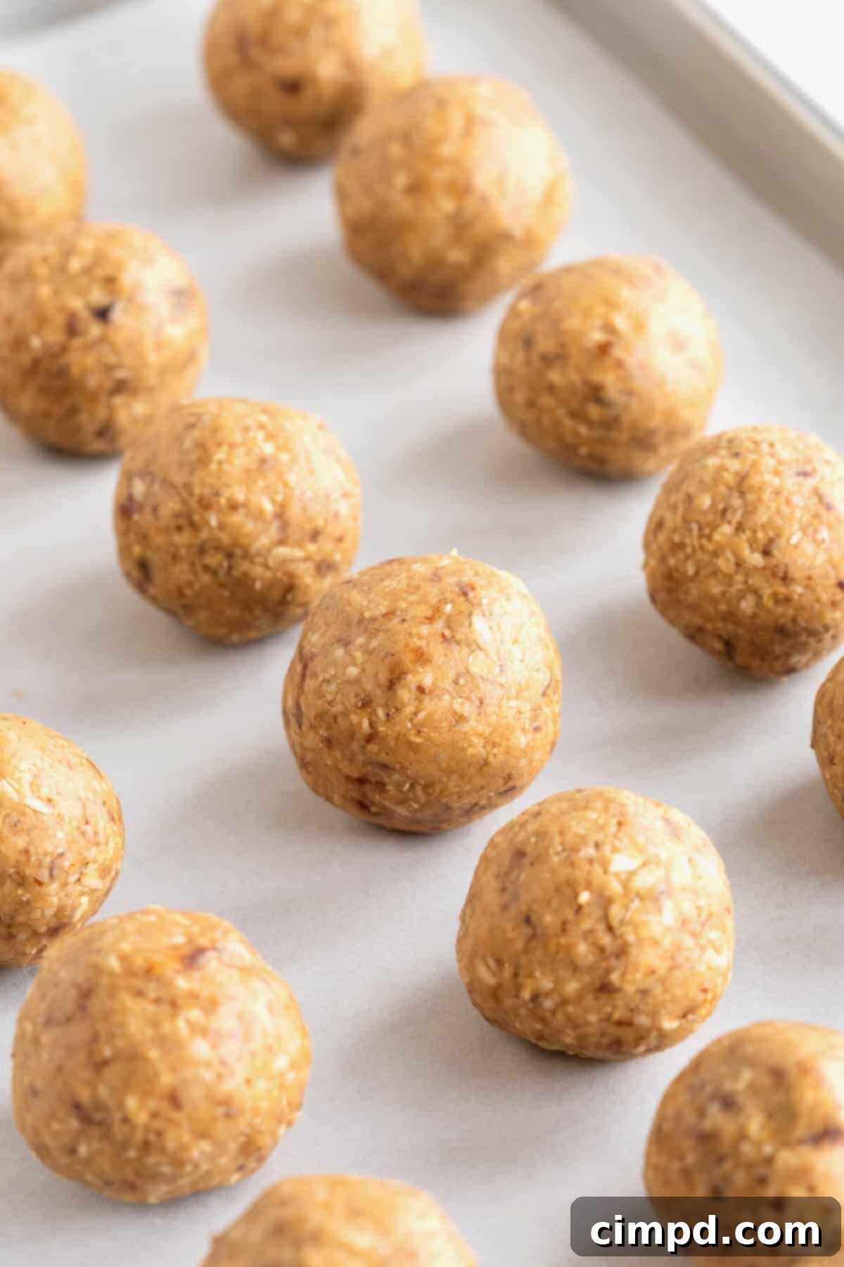 Wholesome Energy Bites 8 A parchment lined aluminum baking sheet filled with energy balls.