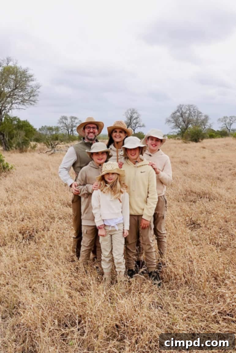 A family wearing muted colors standing together in the African bush, ready for safari.