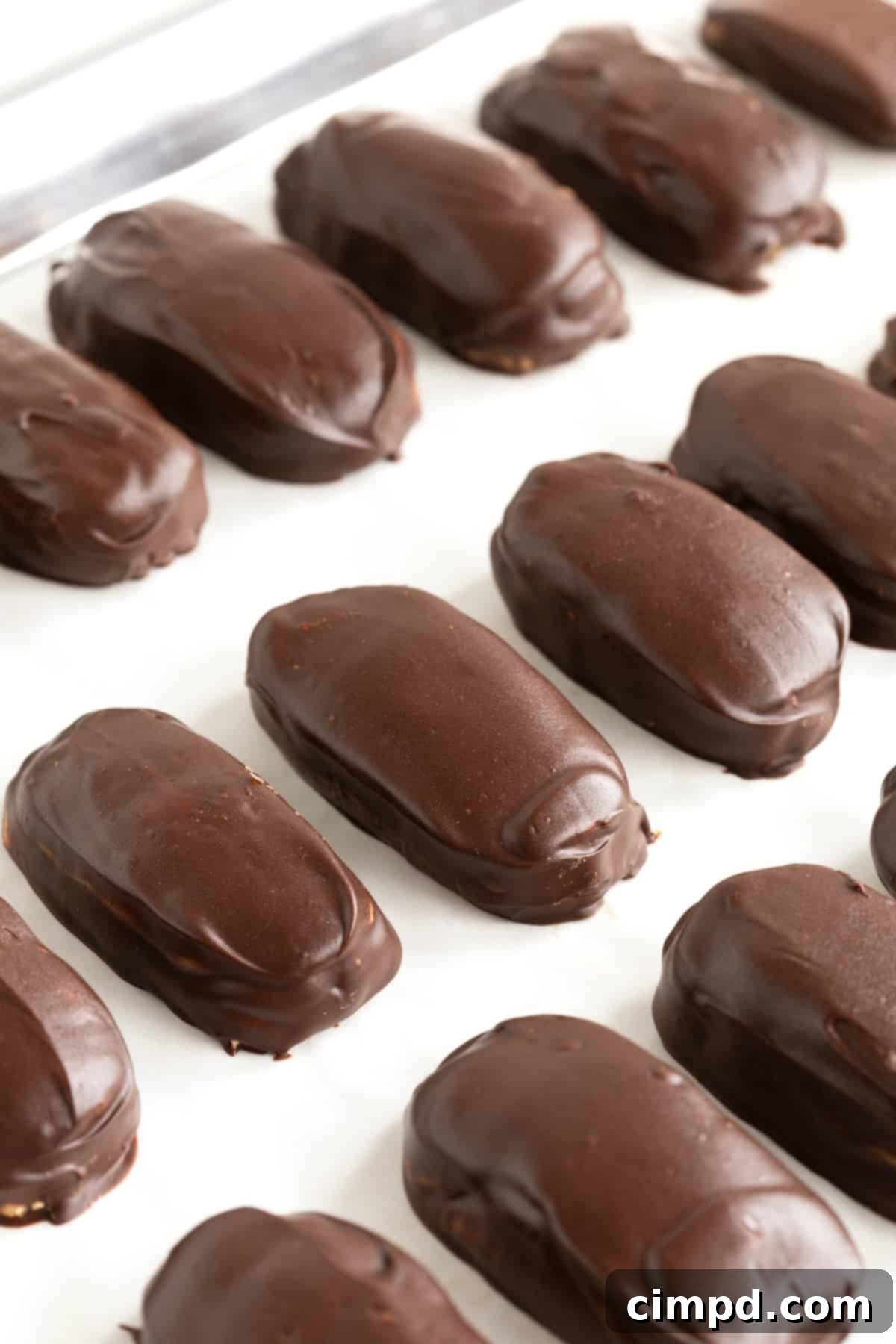 Chewy Homemade Snickers Treats 11 Neatly arranged rows of tempting homemade Snickers bites on a parchment-lined aluminum baking sheet, showcasing their readiness for storage or enjoyment.