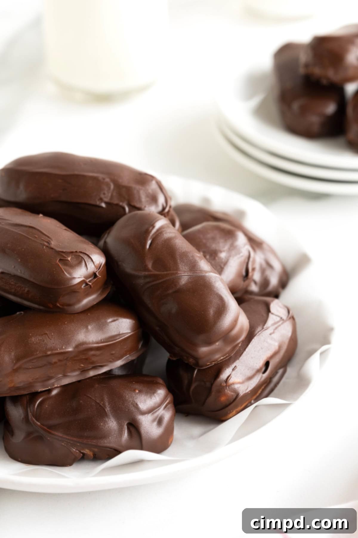 Chewy Homemade Snickers Treats 4 A generous pile of freshly made homemade Snickers bites, glistening with chocolate, on a parchment-lined white plate, ready for serving.