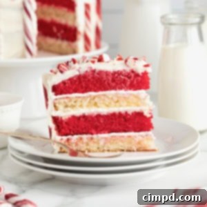 Peppermint Swirl Cake 16 A captivating slice of layered red and white candy cane cake, perfectly presented on a small white dessert plate, enticingly ready for a bite.