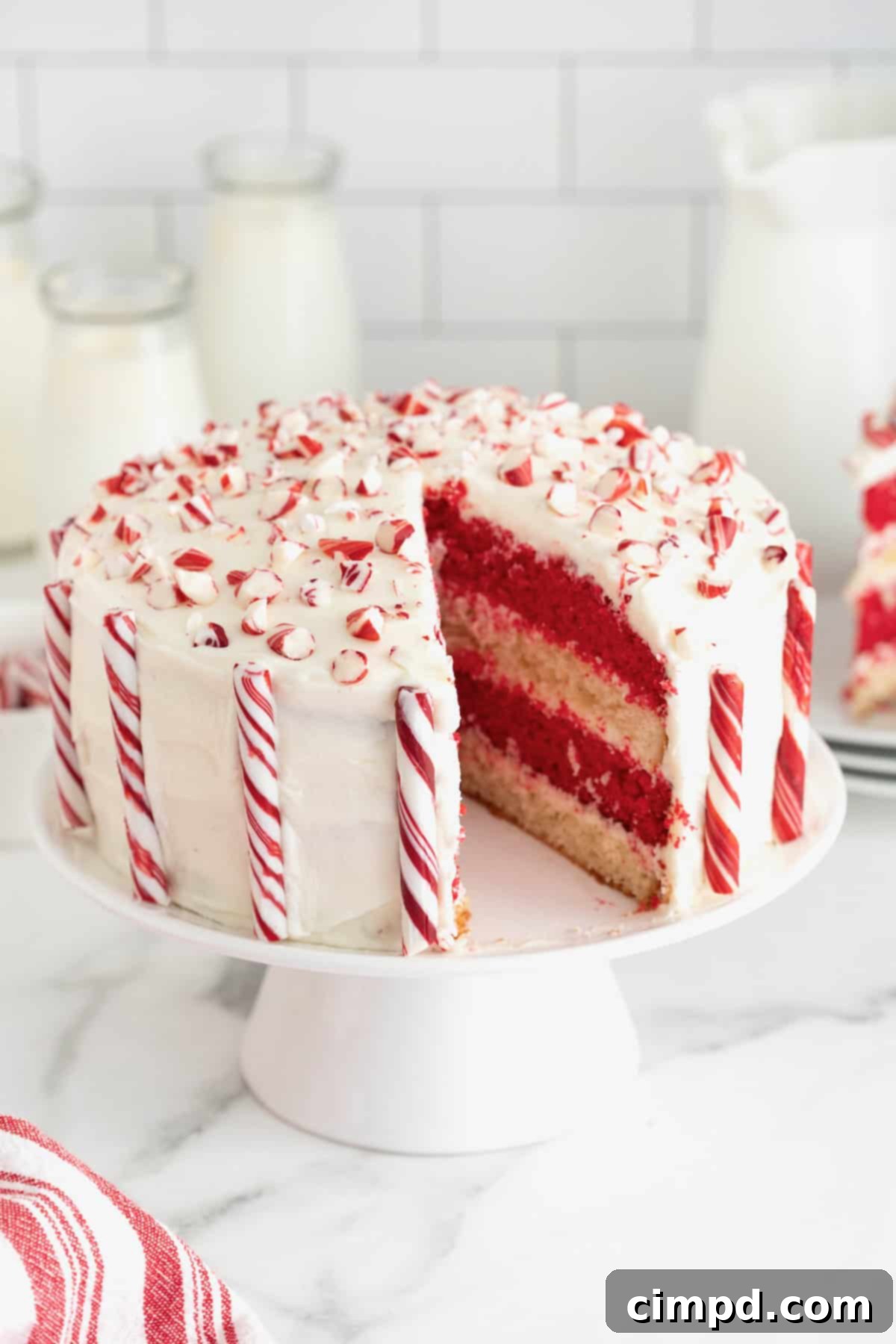 Peppermint Swirl Cake 4 An enticing candy cane cake with a piece elegantly removed, showcasing the vibrant red and white alternating layers within, inviting a closer look.