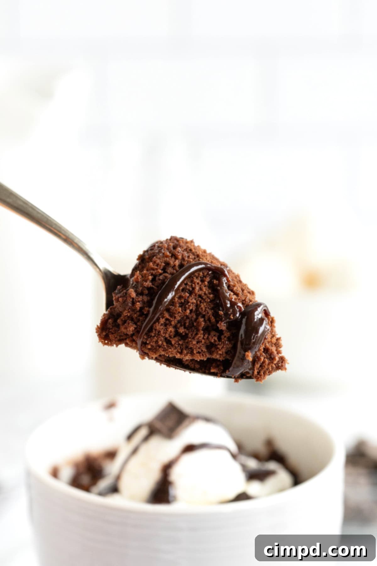 Speedy Chocolate Mug Brownie 3 A close-up shot of a spoonful of warm, fudgy brownie, glistening with a drizzle of chocolate syrup, ready to be enjoyed.