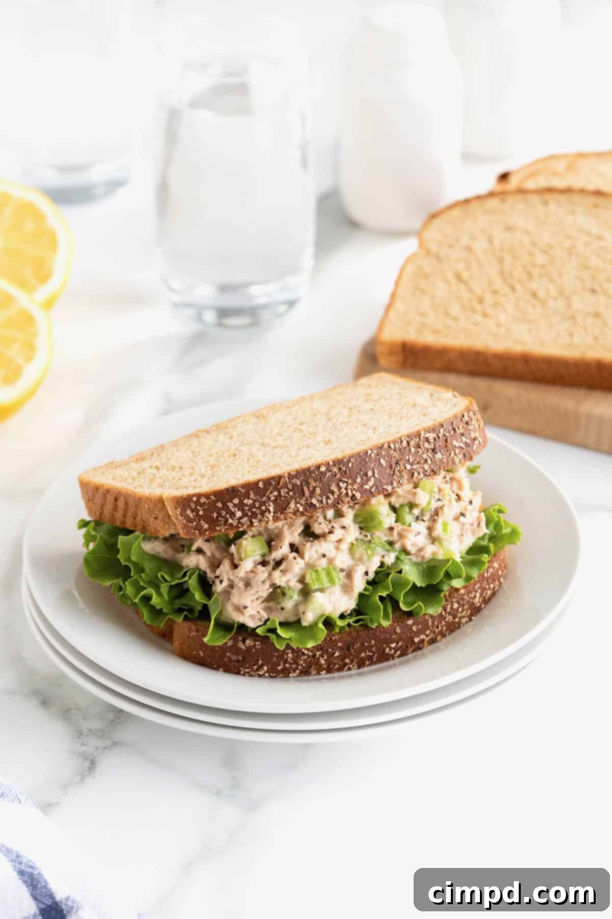 My Tuna Salad 3 Tuna salad sandwich on a stack of white plates on a white marble counter.