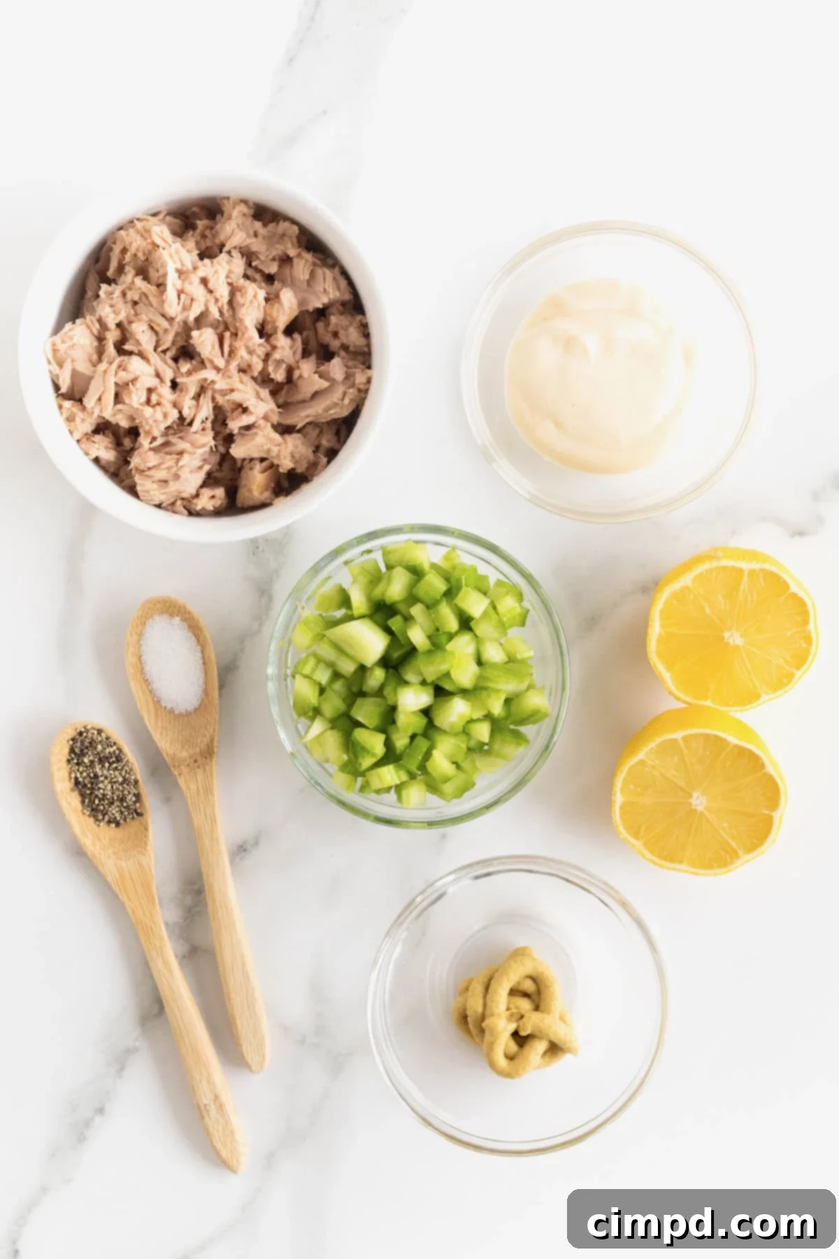 My Tuna Salad 5 Ingredients to make Tuna Salad for One in small dishes on a white marble counter. There is a lemon cut in half next to the bowls.
