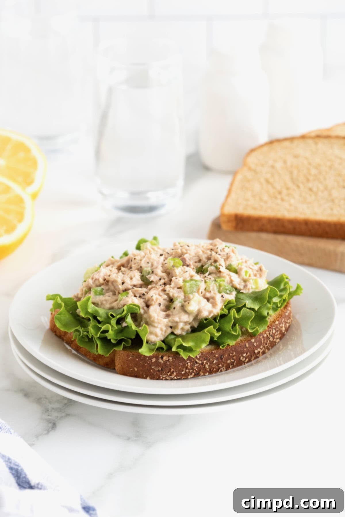 My Tuna Salad 7 Tuna salad sandwich on a stack of white plates on a white marble counter.
