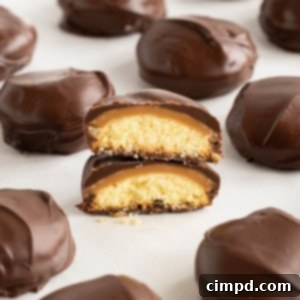 Homemade Twix bites on a parchment lined surface. One bite is cut in half with both halves stacked together to reveal the inside of the candy.