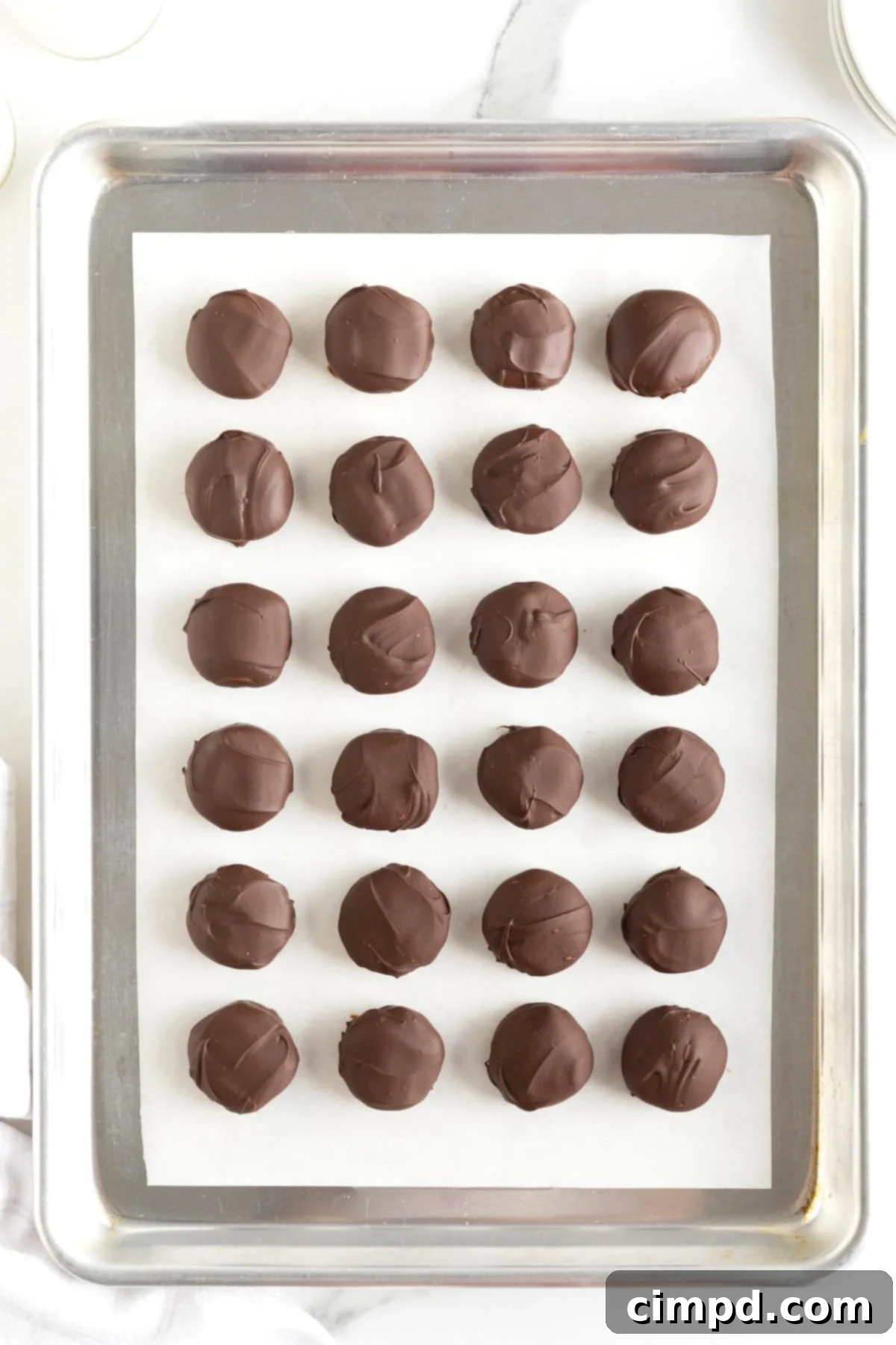 A parchment lined aluminum baking sheet with 24 Twix Bites in even rows.