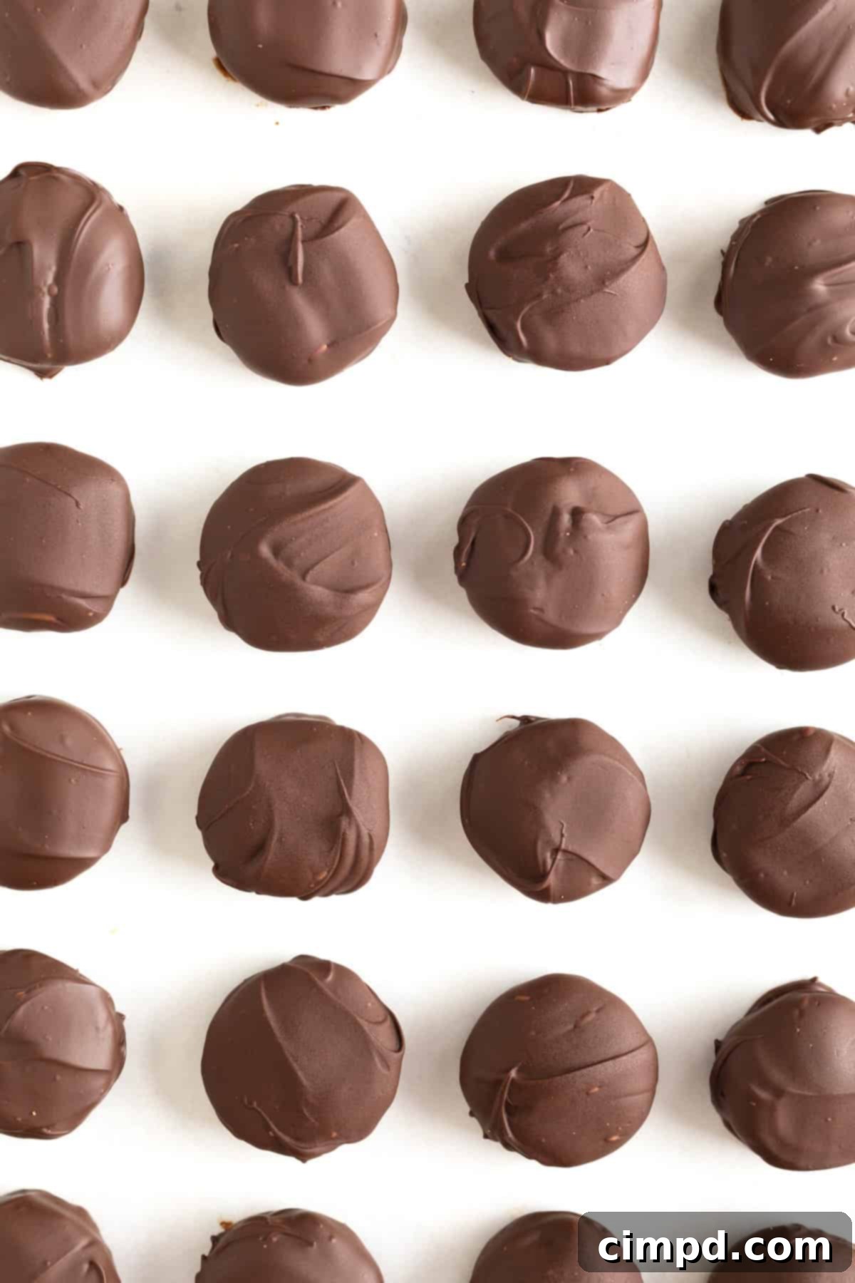 A parchment lined aluminum baking sheet with 24 Twix Bites in even rows.