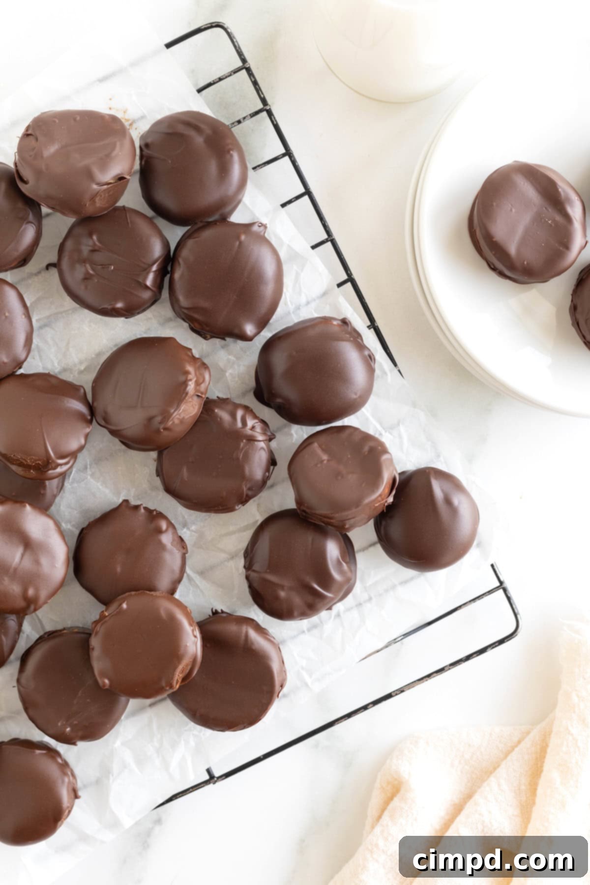 Three Ingredient Peanut Butter Cups 11 A generous and tempting pile of homemade peanut butter cups, artfully arranged on a parchment-lined metal cooling rack, displaying their irresistible texture.