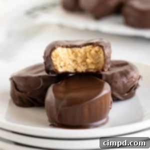 Three Ingredient Peanut Butter Cups 13 Four peanut butter cups on a stack of three small white plates. The top peanut butter cup has a bite out of it.