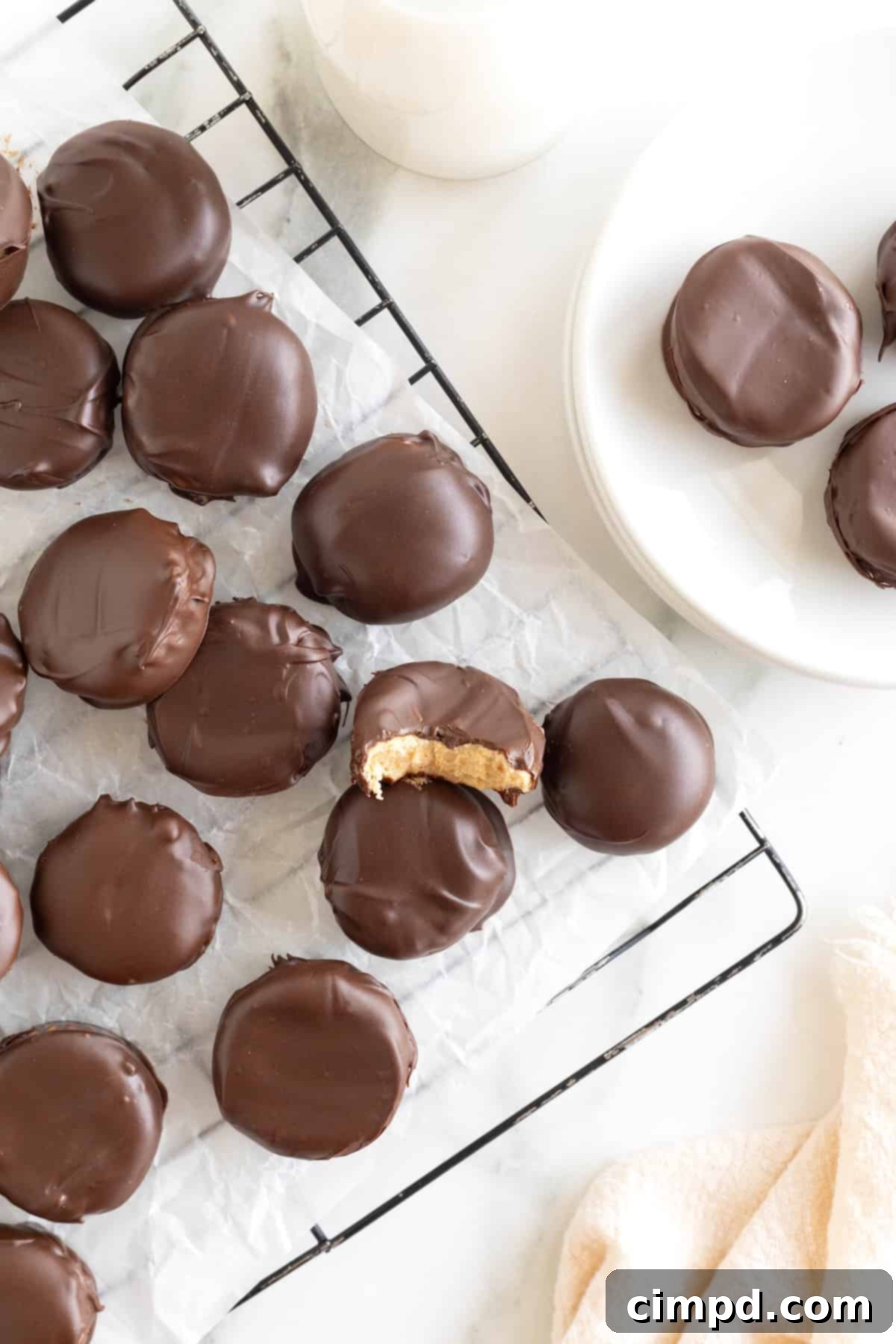 Three Ingredient Peanut Butter Cups 4 A generous pile of freshly made homemade peanut butter cups, arranged neatly on a parchment-lined metal cooling rack, ready to be enjoyed.