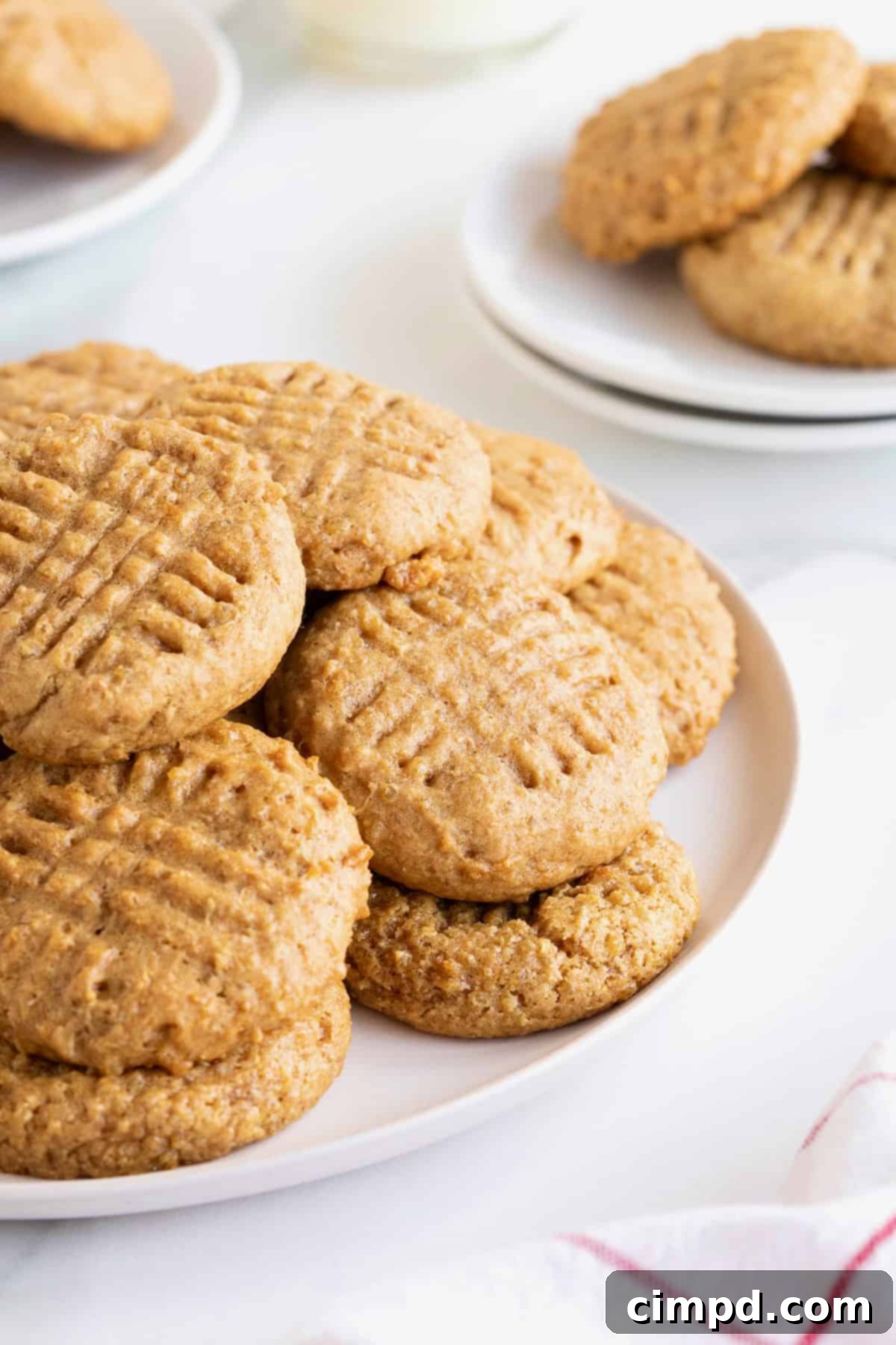 Wholesome Peanut Butter Quinoa Cookies 2 A large white serving plate of golden-brown peanut butter quinoa cookies on a white marble counter, showcasing their inviting texture.