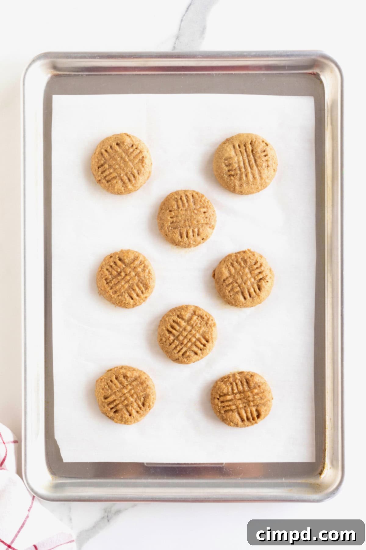 Wholesome Peanut Butter Quinoa Cookies 8 A parchment-lined sheet pan showcasing eight freshly baked peanut butter quinoa cookies, perfectly spaced and golden-brown, ready for cooling.