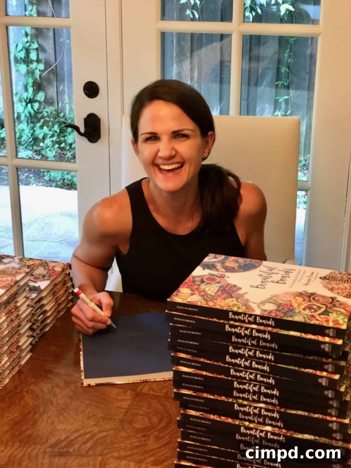 Cookbook author Maegan Brown signing a copy of her best-selling Beautiful Boards Cookbook with a personal touch.