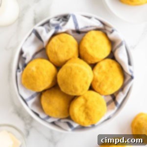 A large white serving bowl lined with a tea towel filled with pumpkin biscuits.