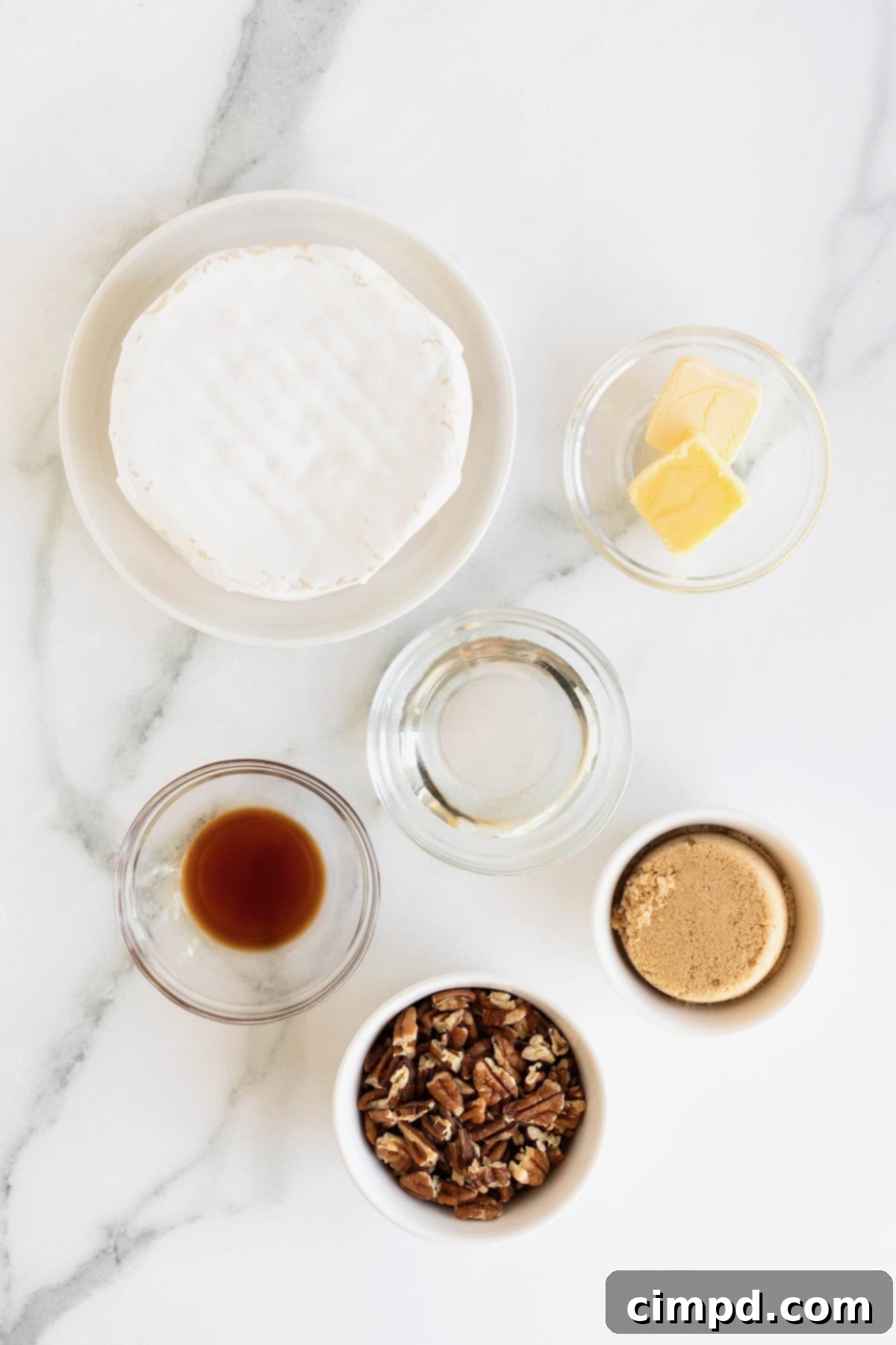 Caramel Pecan Baked Brie 5 Ingredients to make Pecan Pie Baked Brie in small glass dishes on a white marble counter.