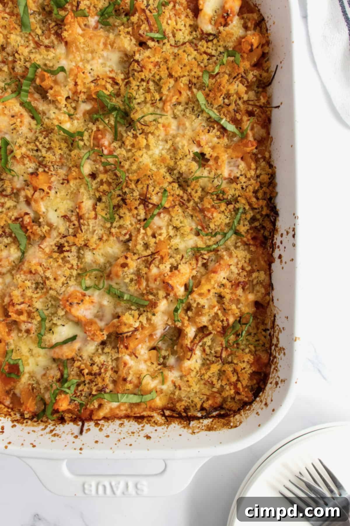 A white casserole dish of chicken parmesan casserole garnished with ribbons of fresh basil.