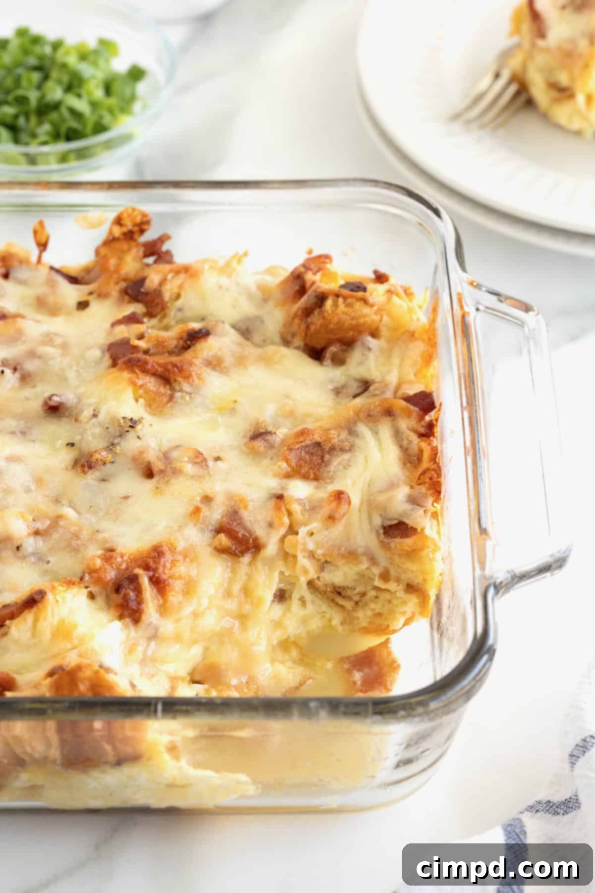 Golden Croissant Breakfast Bake 4 A close-up view of a glass baking dish filled with golden-brown croissant breakfast casserole, fresh out of the oven.