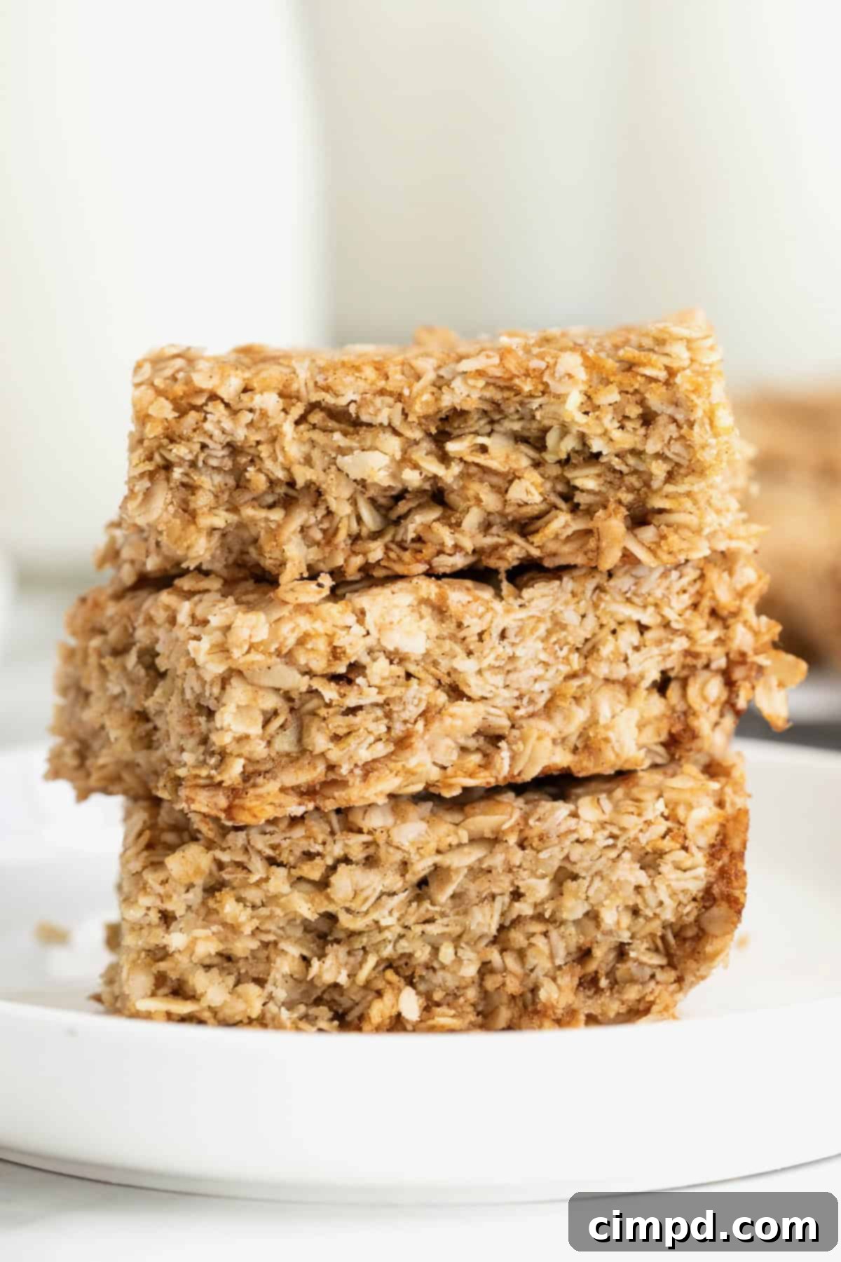 Three crunch oatmeal bars stacked on a small white plate, showcasing their golden-brown color and texture.