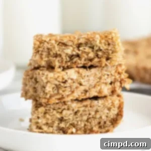 Three crunchy oatmeal bars stacked on a small white plate, ready to be served.