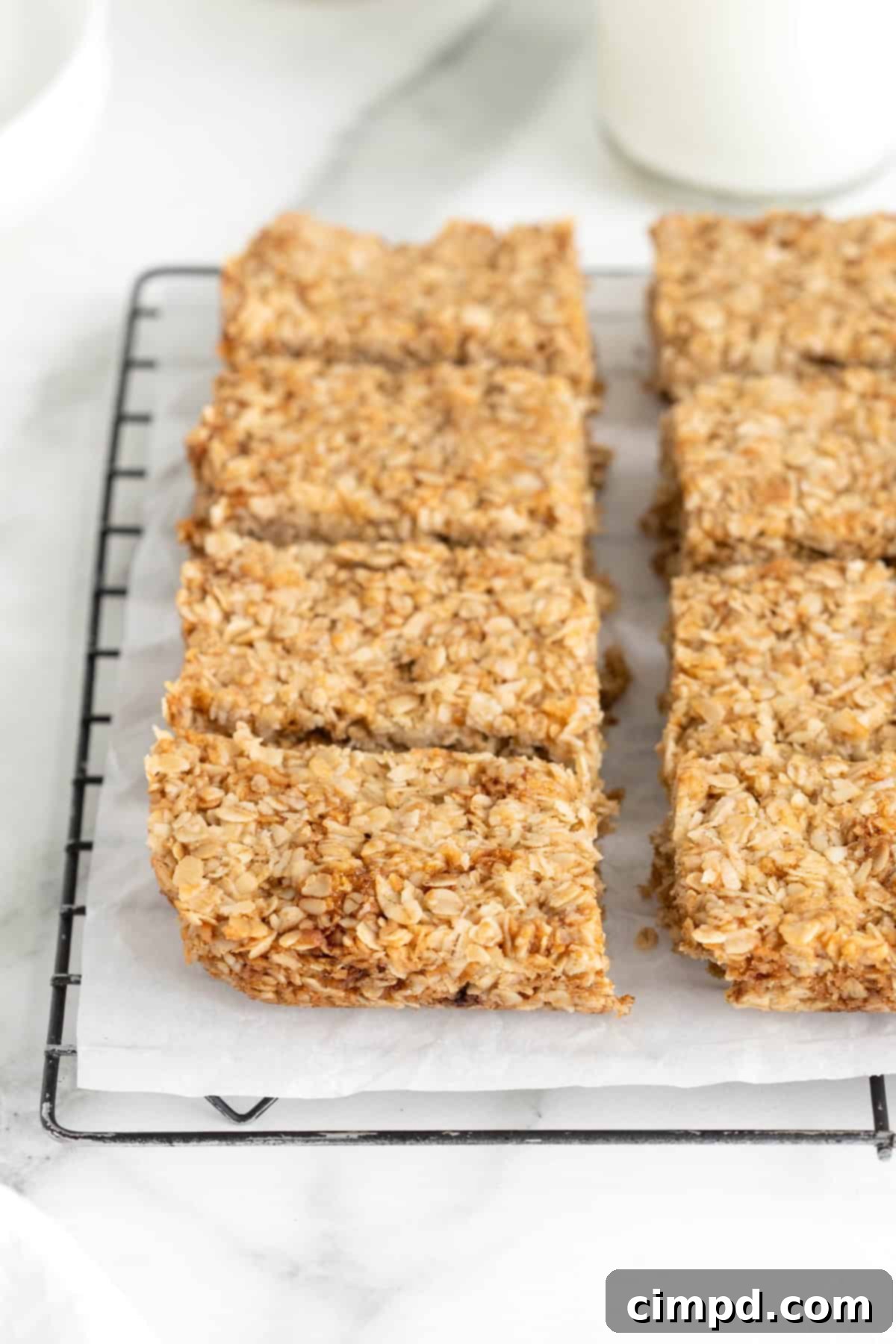 Eight oatmeal crunchies bars neatly arranged on a parchment-lined cooling rack, ready to be enjoyed.