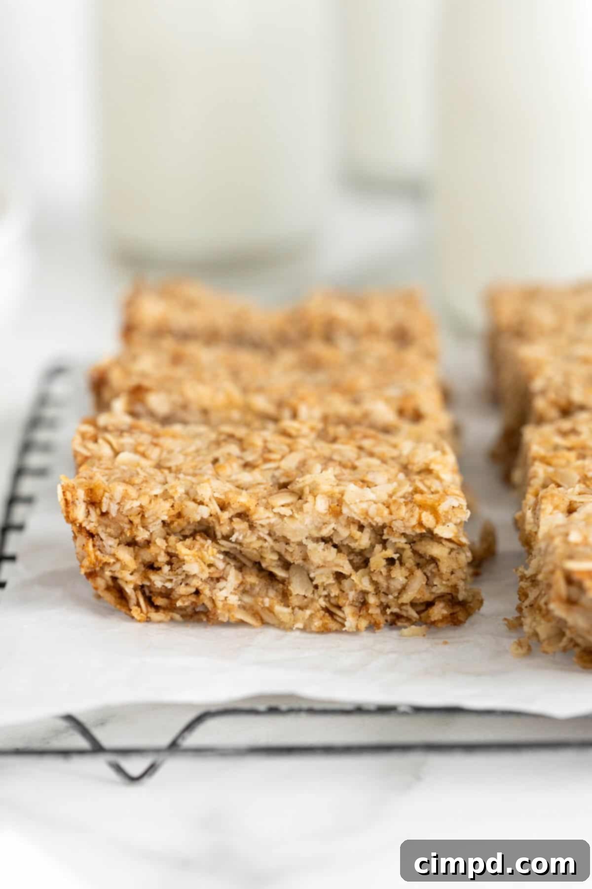 Eight oatmeal crunchies bars on a parchment lined cooling rack, showcasing their golden-brown and textured surface.