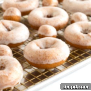 Homemade glazed donuts on a cooling rack over an aluminum sheet pan.