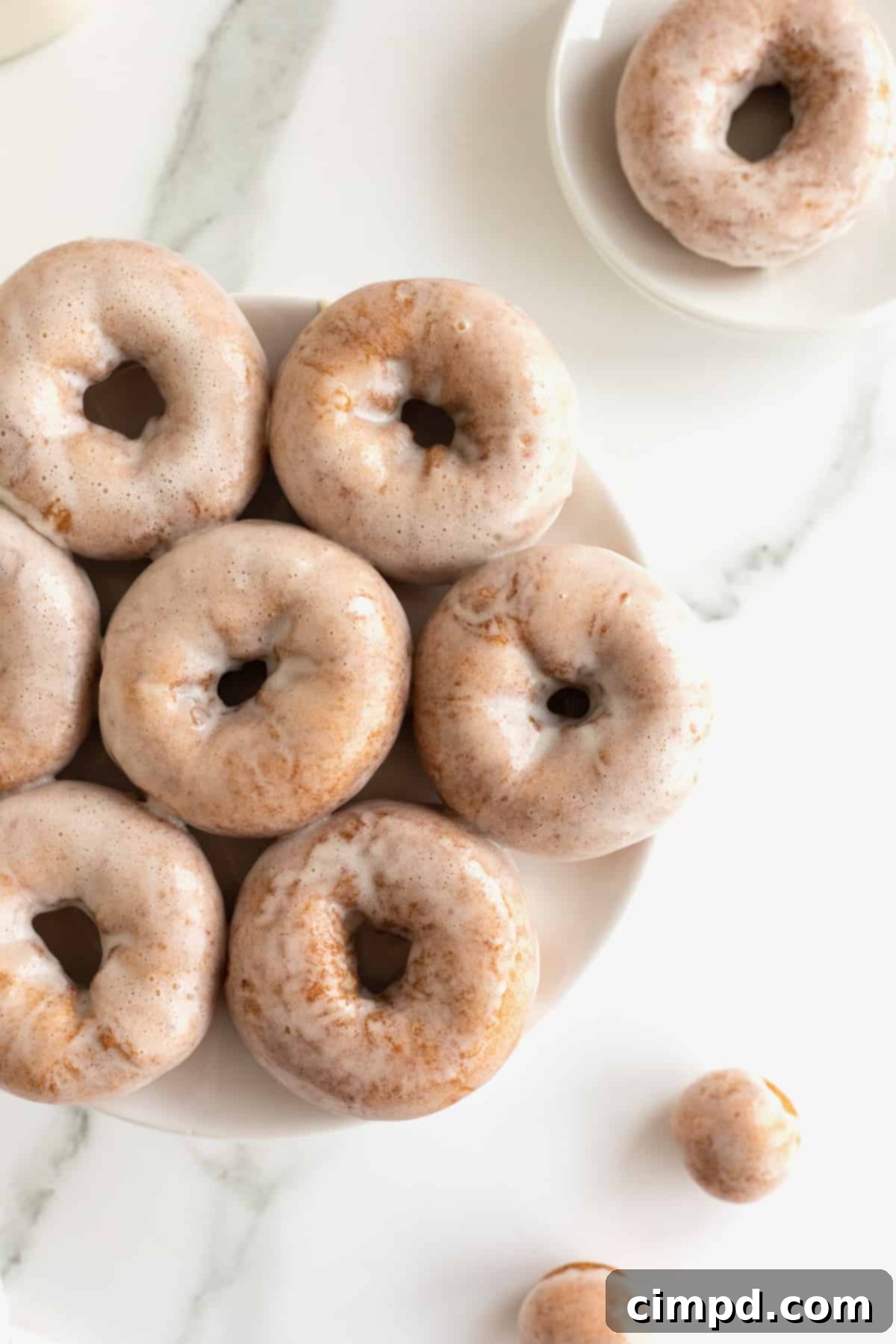 7 homemade glazed old fashioned donuts on a white serving dish.